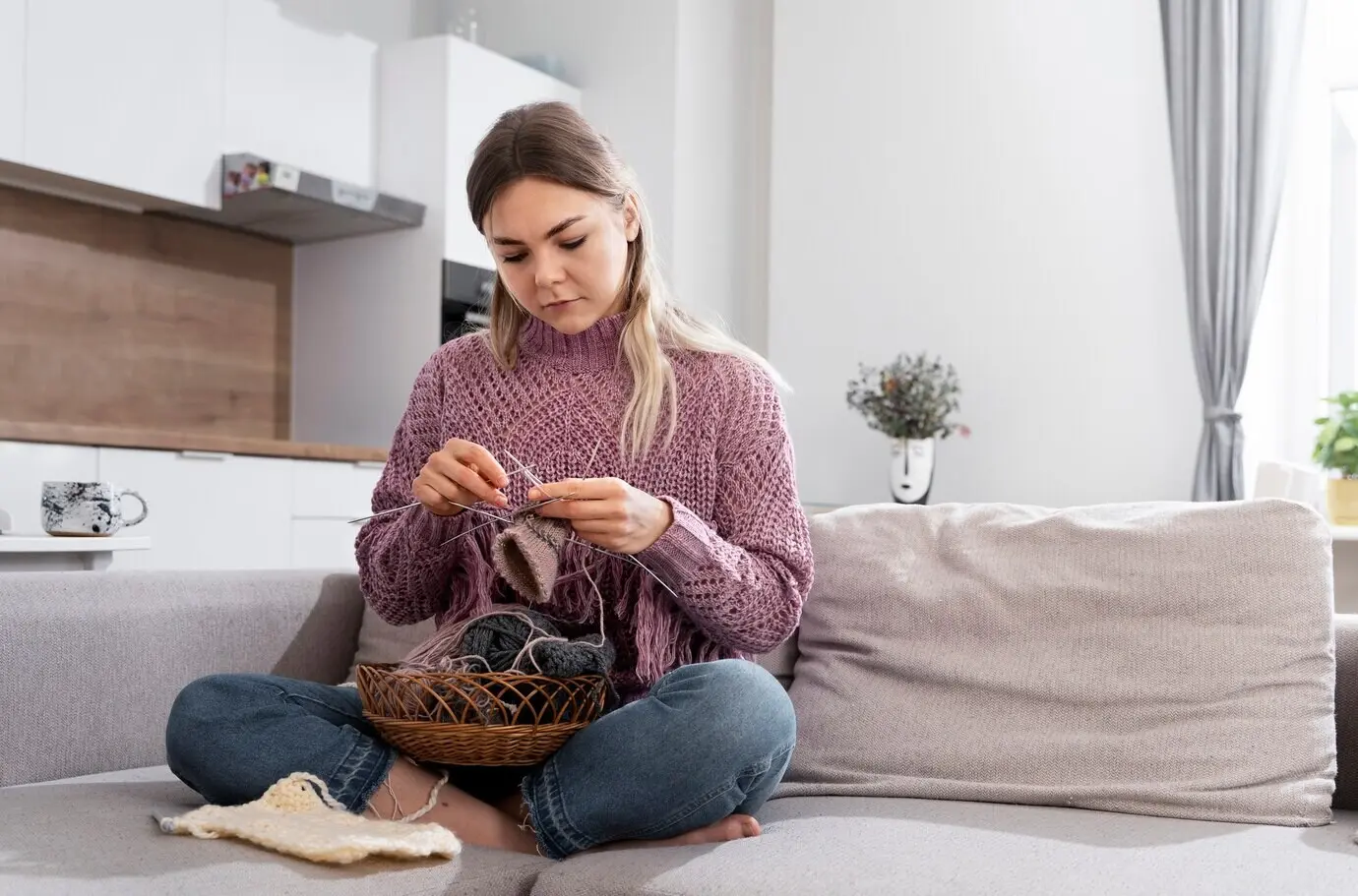 Junge Frau strickt, während sie sich entspannt.
